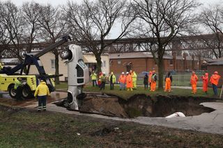 In the spring of 2013, a 15-foot-deep (4.6 meters) sinkhole swallowed three vehicles on a residential street in the South Deering neighborhood in Chicago. Here, workers get ready to pull the "swallowed" truck out of the sinkhole on April 18.