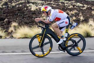 Kristian Blummenfelt riding a Cadex tri bike with Kona lava in the background