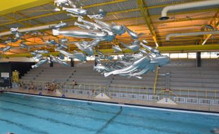 Silver fish structures above a swimming pool