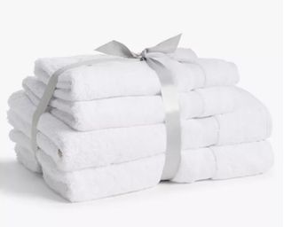 John Lewis & Partners Egyptian Cotton 4 Piece Towel Bale in white, stacked and wrapped up with a silk ribbon