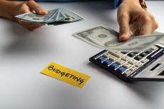 Hands counting money over a calculator