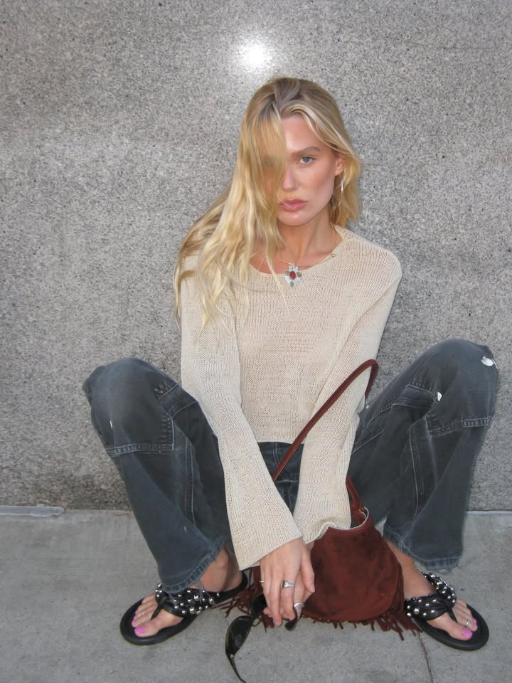 A woman sitting on the ground with icy blonde summer hair.
