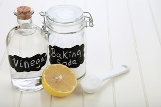 vinegar baking soda in jars and half a lemon on a table
