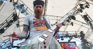 Brent Hinds plays his lucite Electrical Guitar Company V onstage with Mastodon and pulls a face for the camera