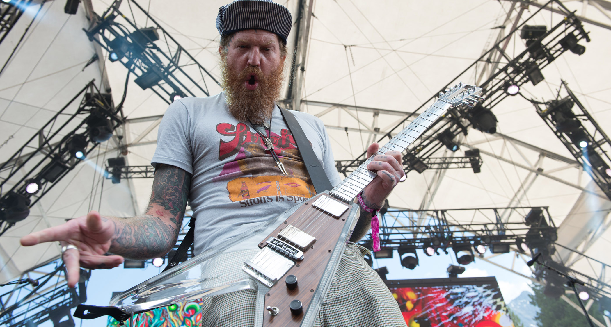 Brent Hinds plays his lucite Electrical Guitar Company V onstage with Mastodon and pulls a face for the camera