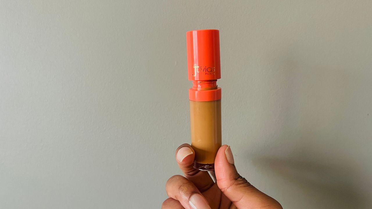 A person holding a slightly opened Juvia's Place I Am Magic Concealer for the best drugstore concealers.