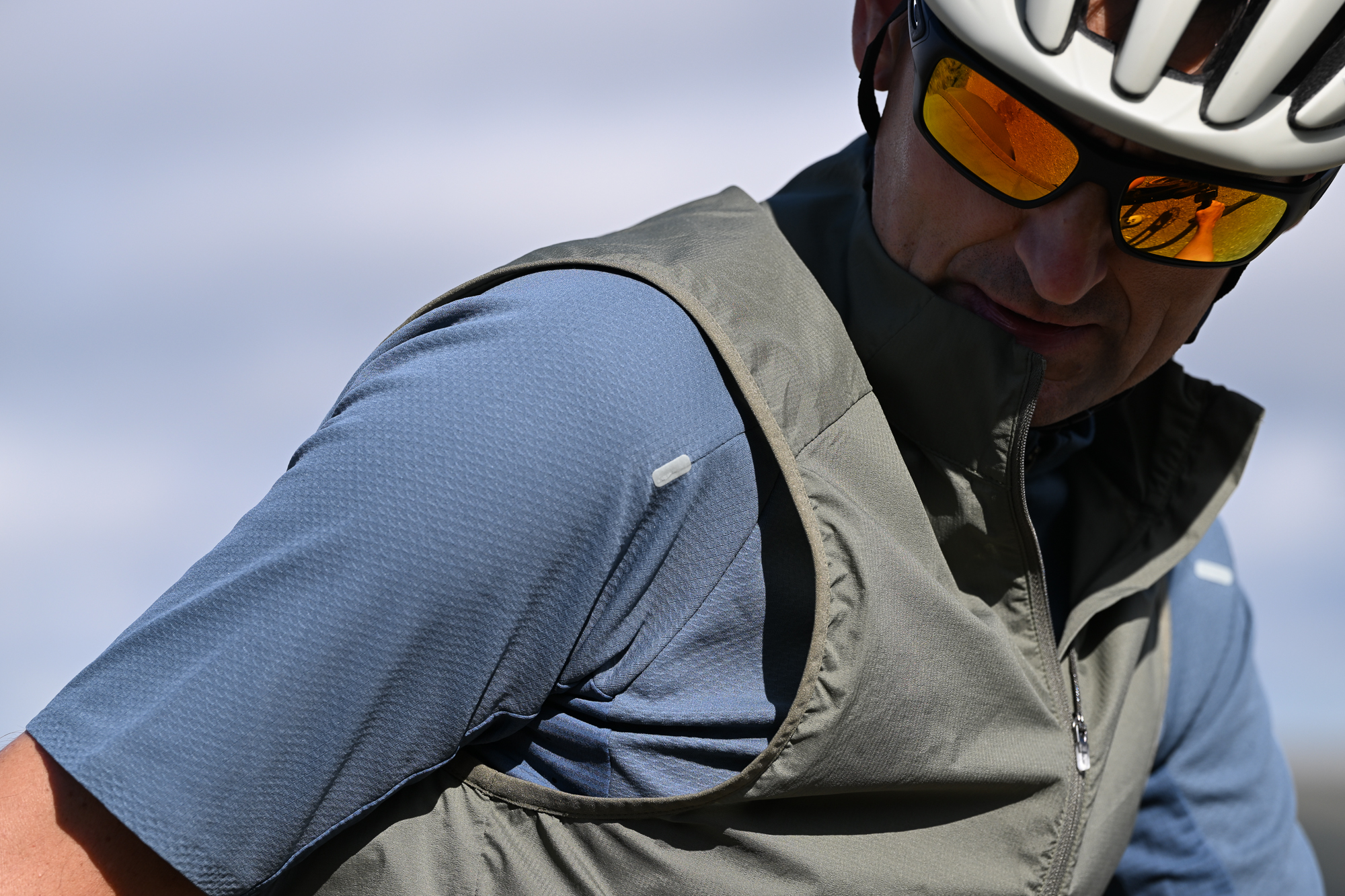 Man wearing a blue jersey, beige helmet and green gilet
