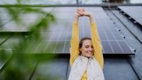 A woman happy standing in front of solar panels