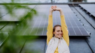 A woman happy standing in front of solar panels