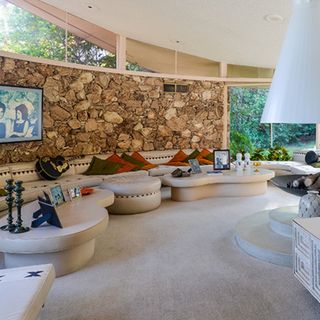 living area with circular sofa and stone work on wall