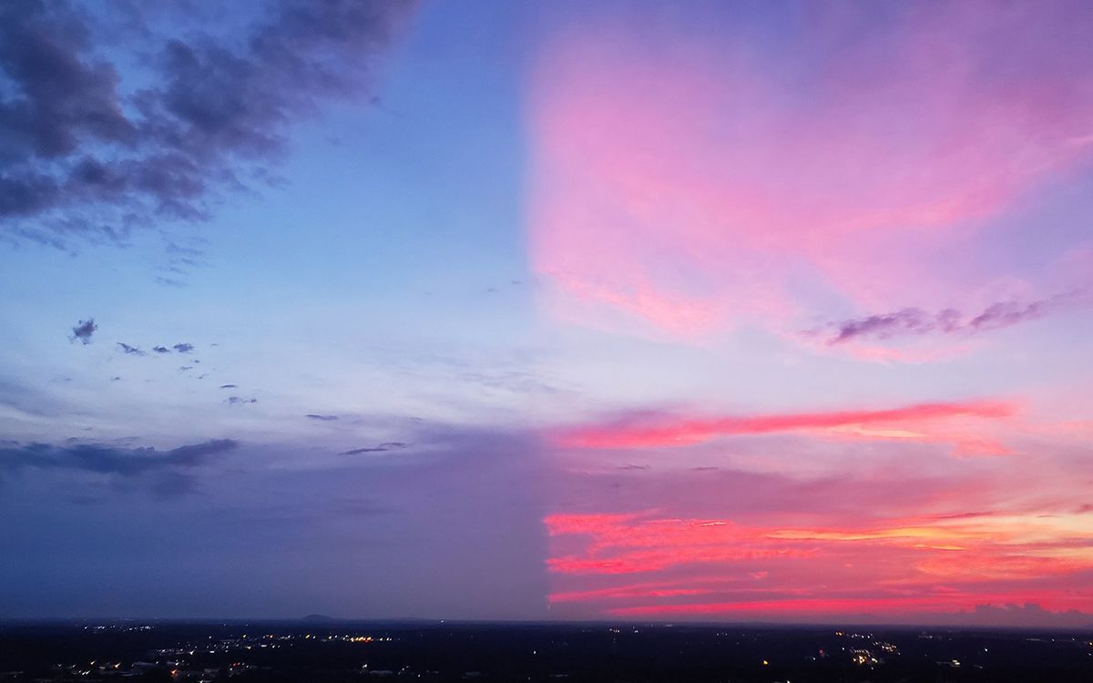 The spectacular colors of this sunset cover only half the sky. A large, distant cloud below the horizon shadows the other half.