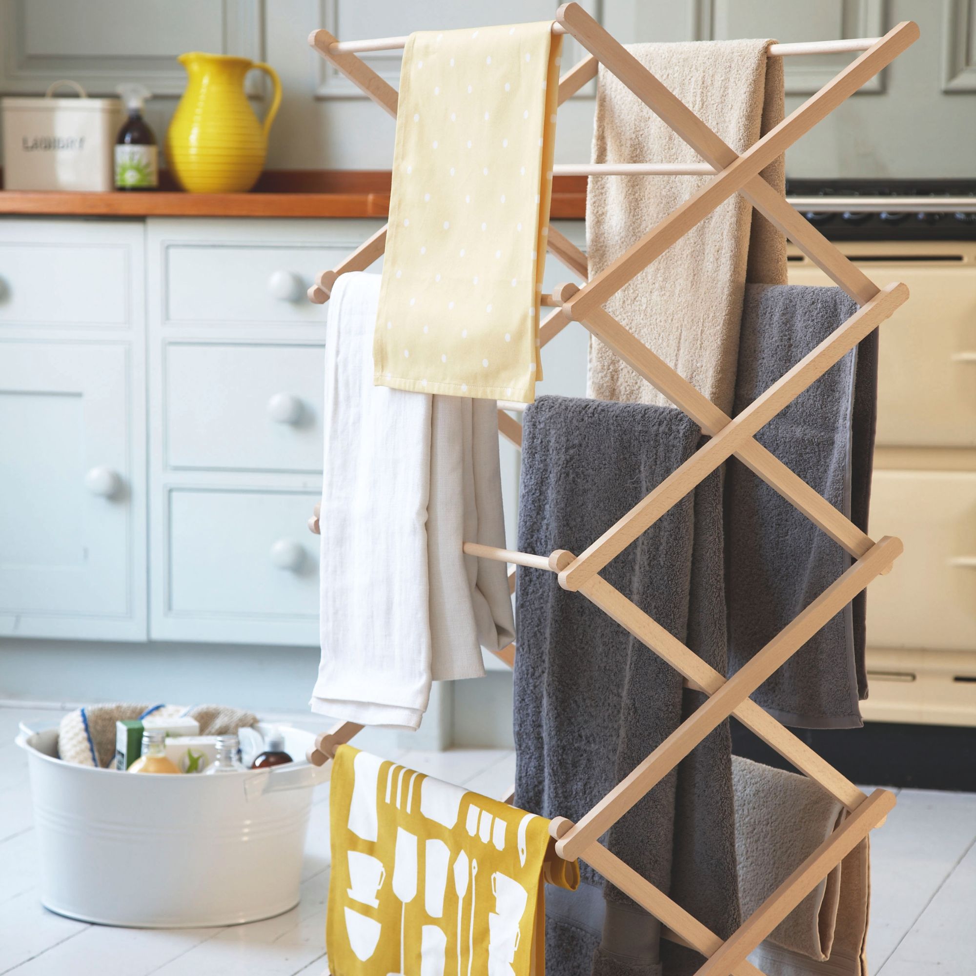 Wooden clothes airer standing in a kitchen with towels hanging on it