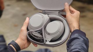 A photo of a person holding up the sony wh-1000xm4 headphones in their charging case