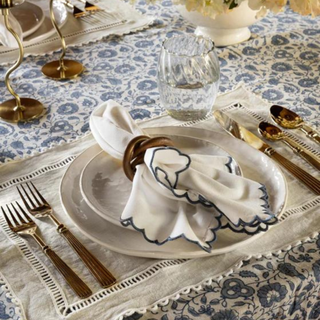 A table set with a napkin and brass silverware.