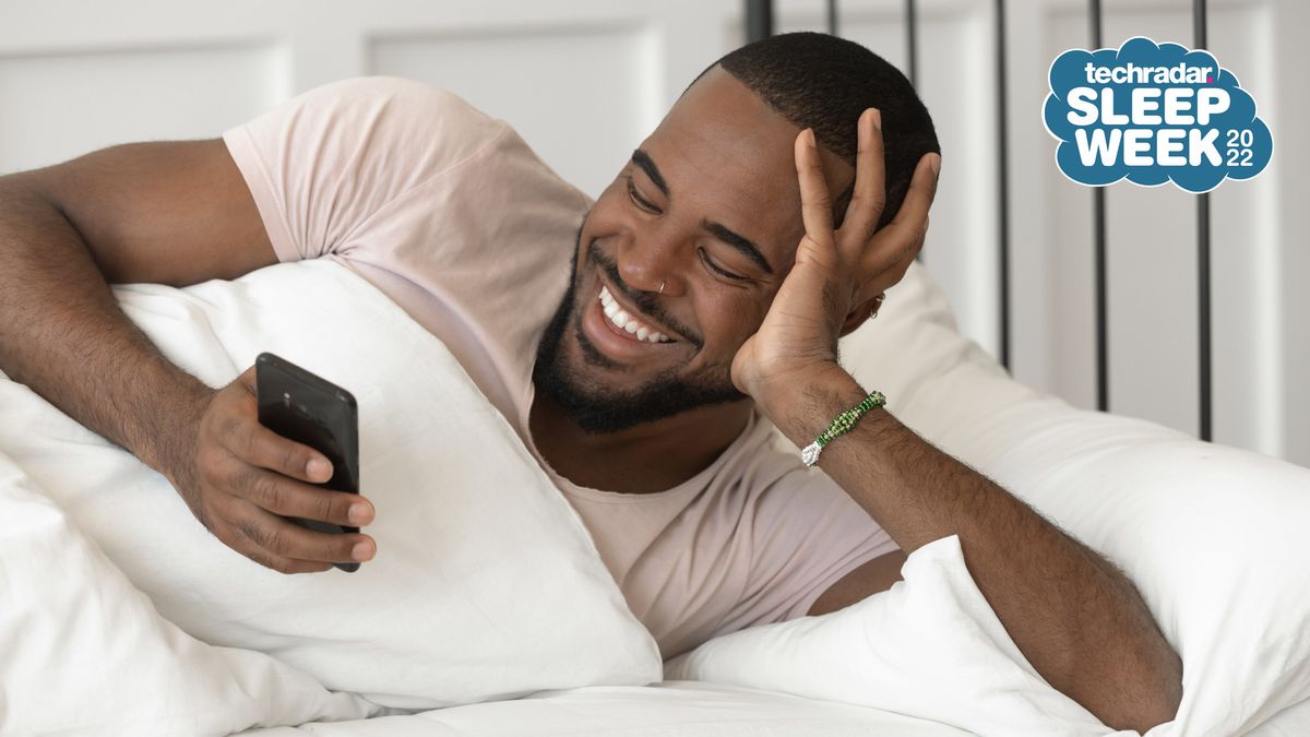 Man lying in bed checking smartphone