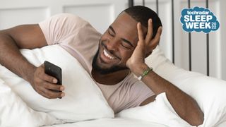 Man lying in bed checking smartphone