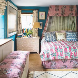 bedroom wall decor idea, bedroom with print and pattern, maximalist, fabric bed canopy, electric blue walls, mother of pearl chest of drawers, coir carpet, artwork, books, ottoman, rug, quilts