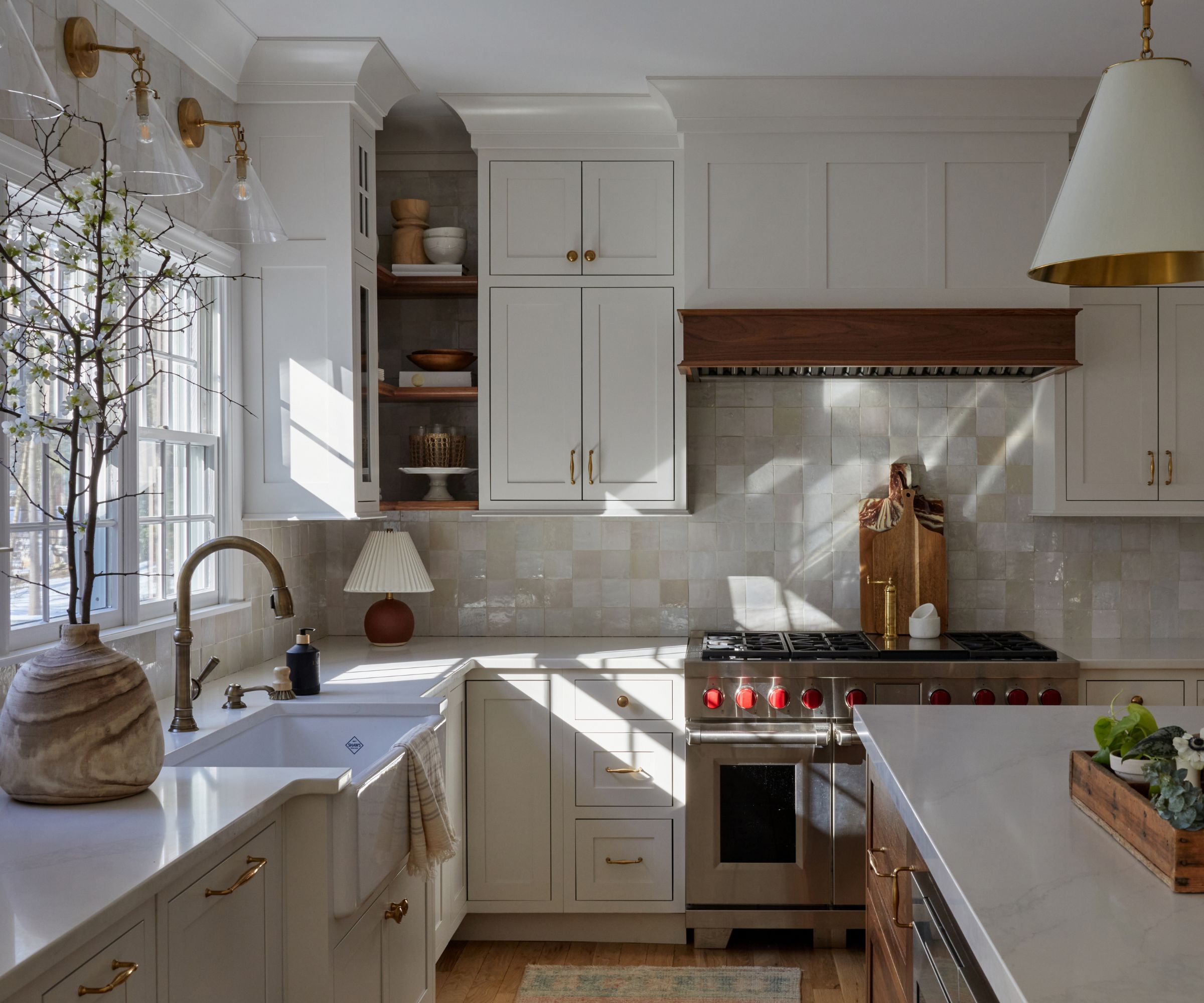 A modern rustic kitchen with warm white cabinets, white countertops and brass details.