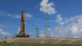NASA's Artemis 1 Space Launch System megarocket and Orion capsule on their Florida launchpad under a blue sky.