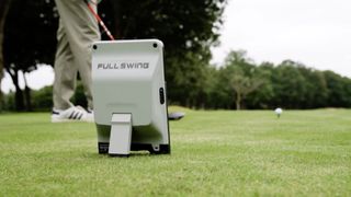 Photo of the FullSwing KIT Launch Monitor set up behind a player driving a golf ball, ready to capture data