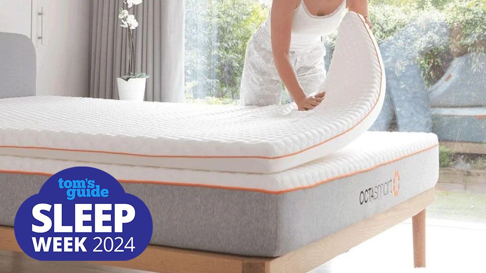 A woman places a Dormeo Octasmart Deluxe Mattress Topper on a white mattress