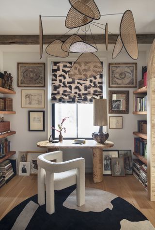 A home office with artworks on the wall, books and a unique lighting piece