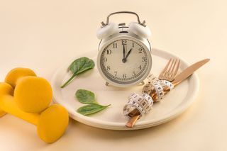 A clock, cutlery and tape measure on a plate