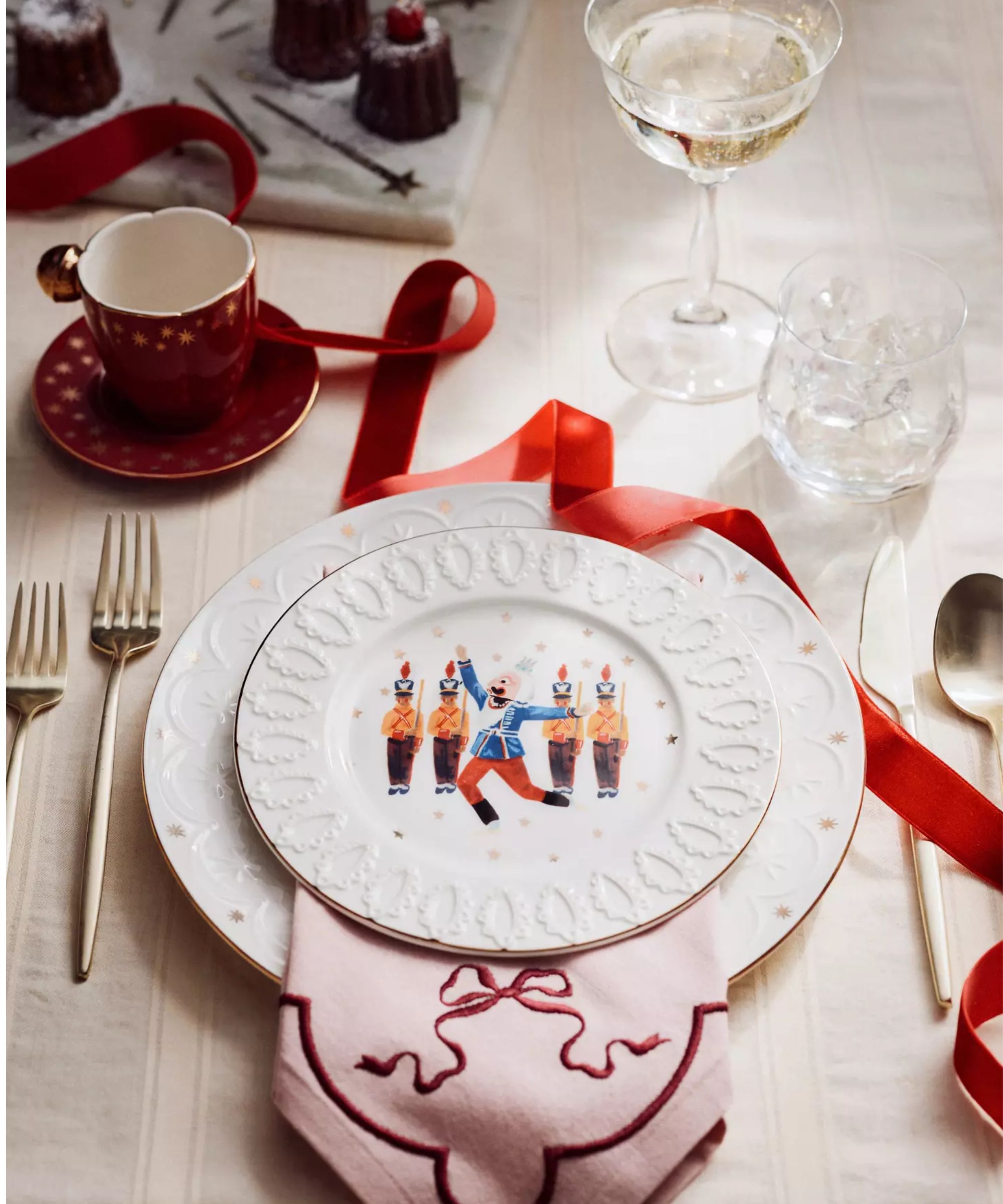 Festive table with white plates, red teacups and saucers, and pale pink napkins with red bows