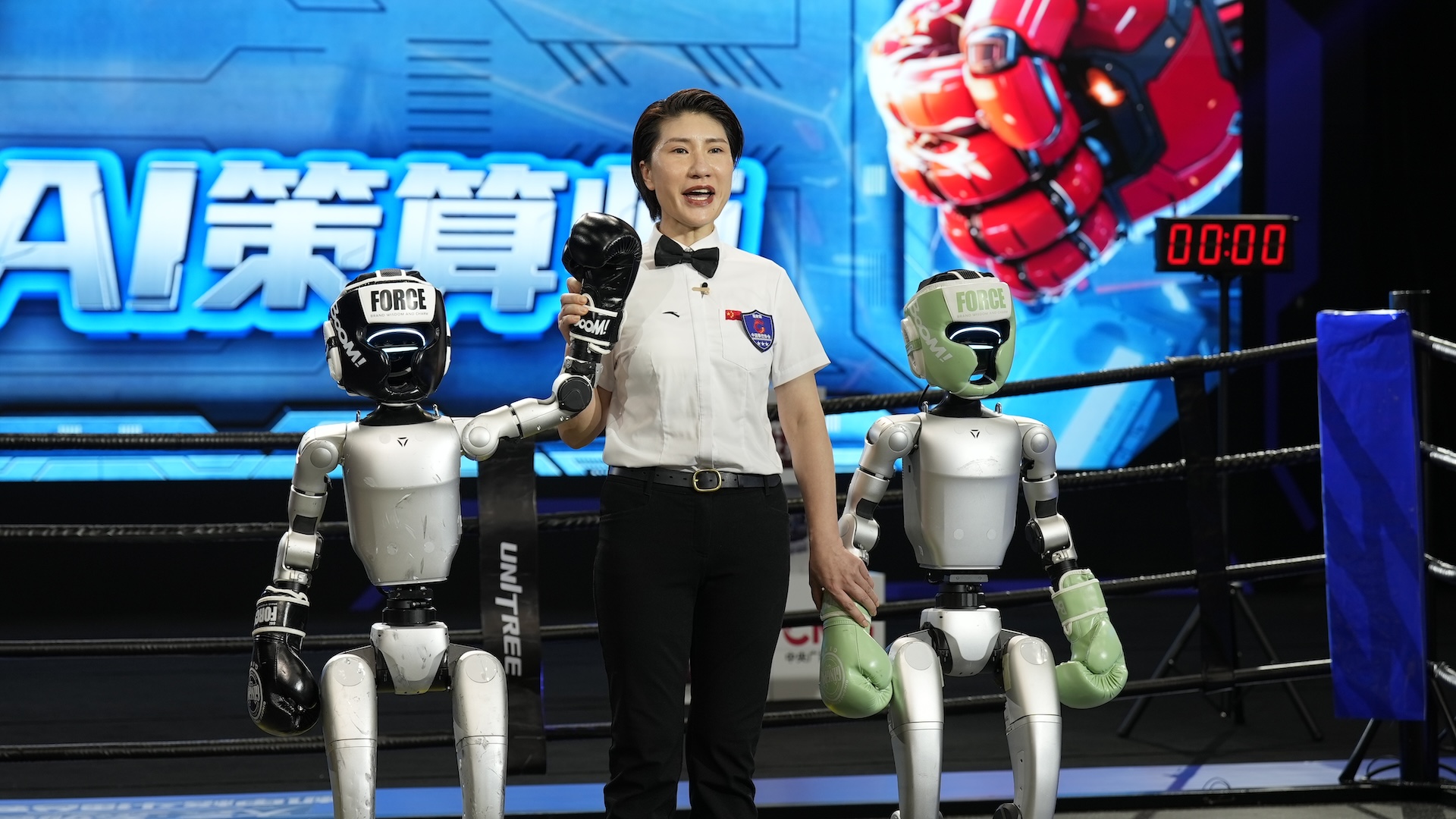 An announcer holds up the hand of a robot that won a boxing match