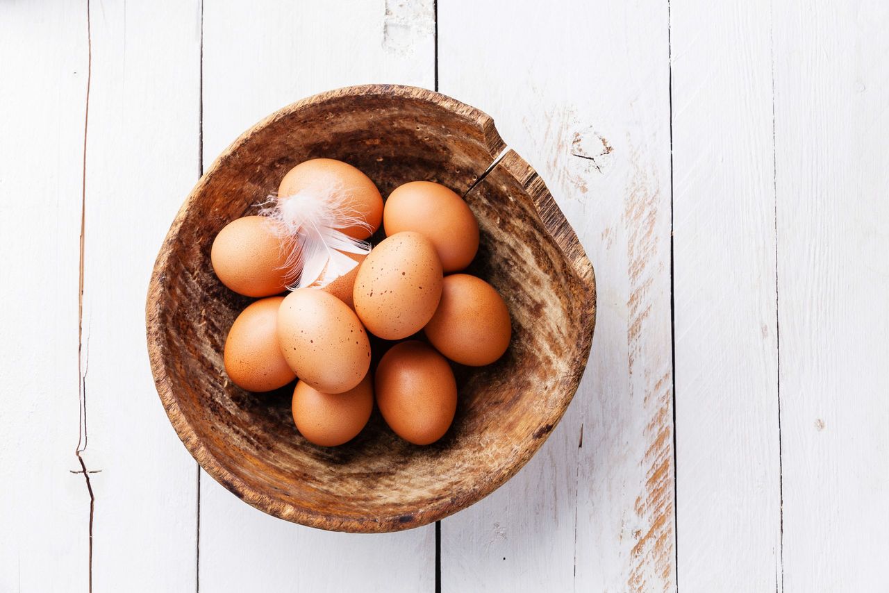 Eggs in a brown bowl on a white surface.