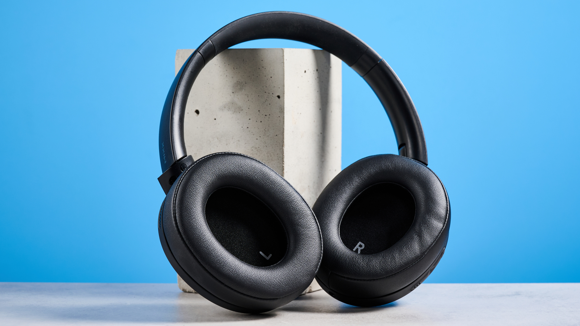 the mixx streamq c4 headphones in black with a blue background showing the soft cups and buttons controls