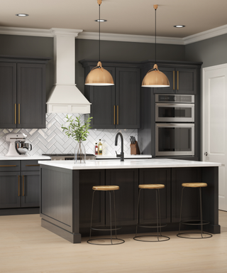 A kitchen with black cabinets, bar stools and a white range hood.