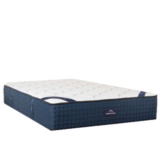 The Dreamcloud Luxury Hybrid bed-in-a-box pictured with a navy base and white quilted top