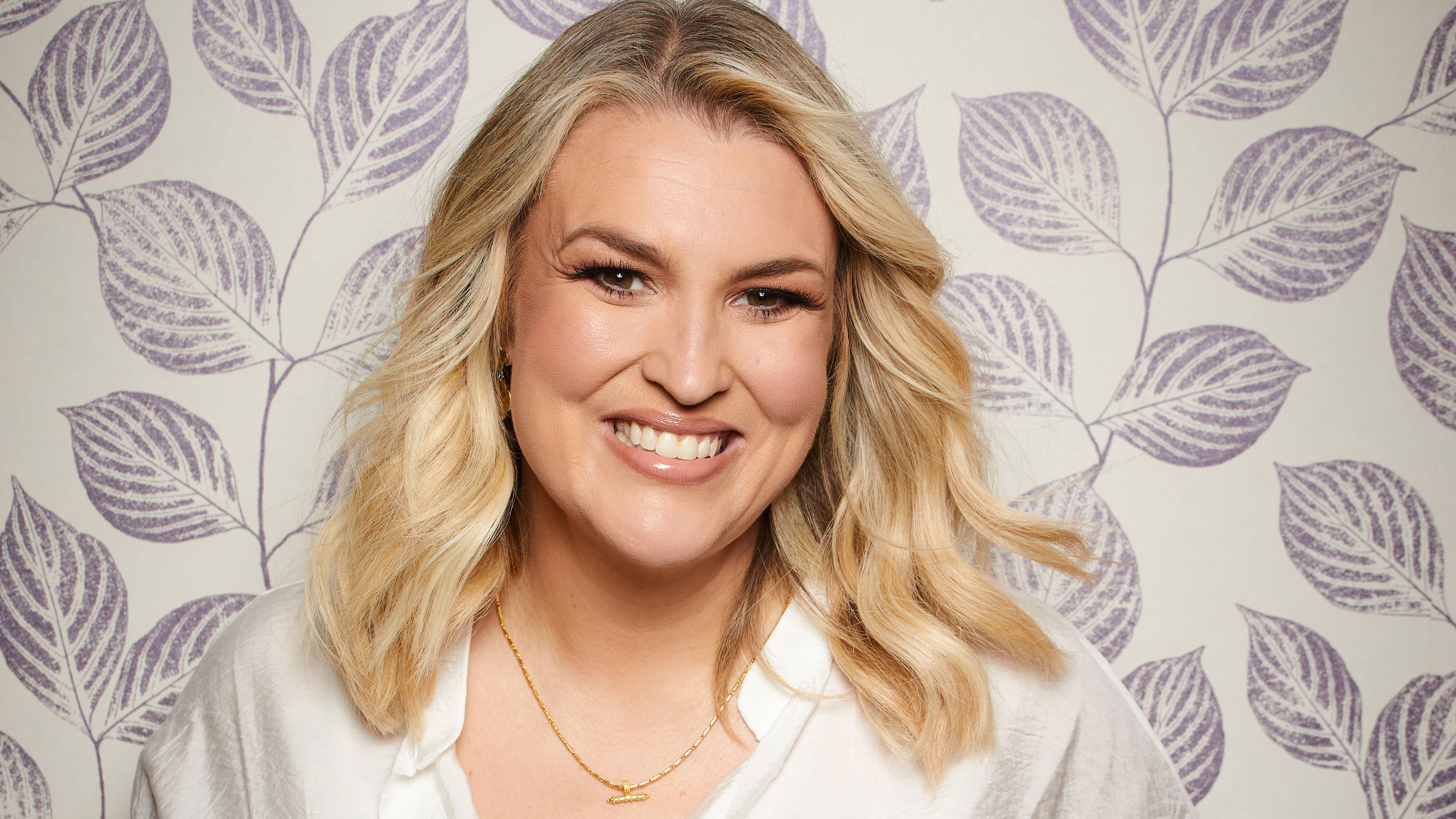 Sara Davies with blonde curled hair and white top