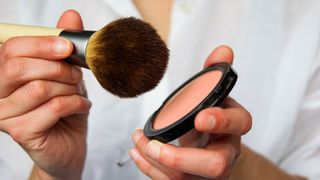 woman tapping brush in face powder