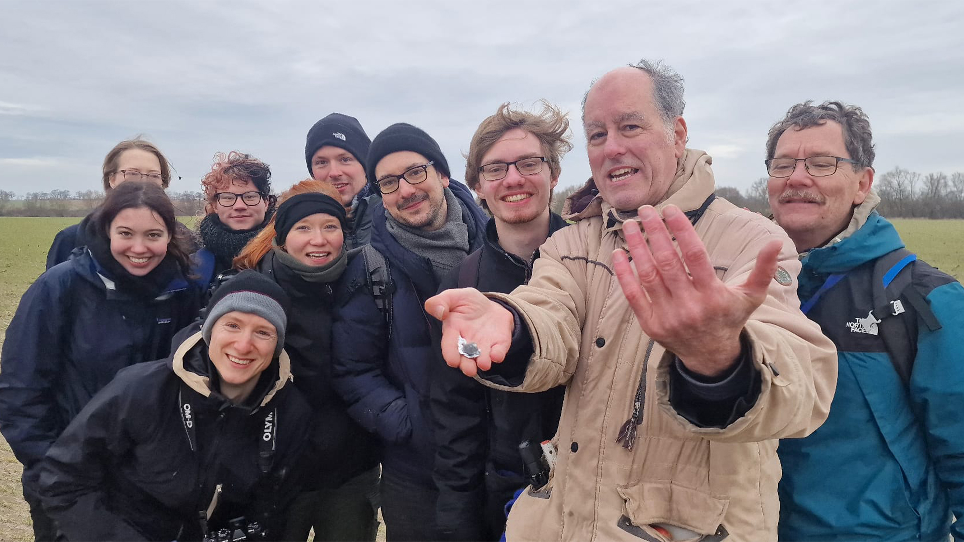 A fragment of 2024 BX1 held by Peter Jenniskens, surrounded by the team who assisted in finding it, now confirmed to be a rare aubrite meteorite.