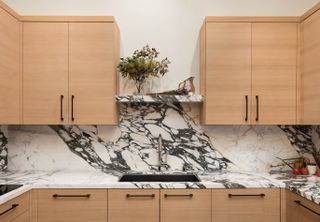 a wood kitchen with marble backdrop