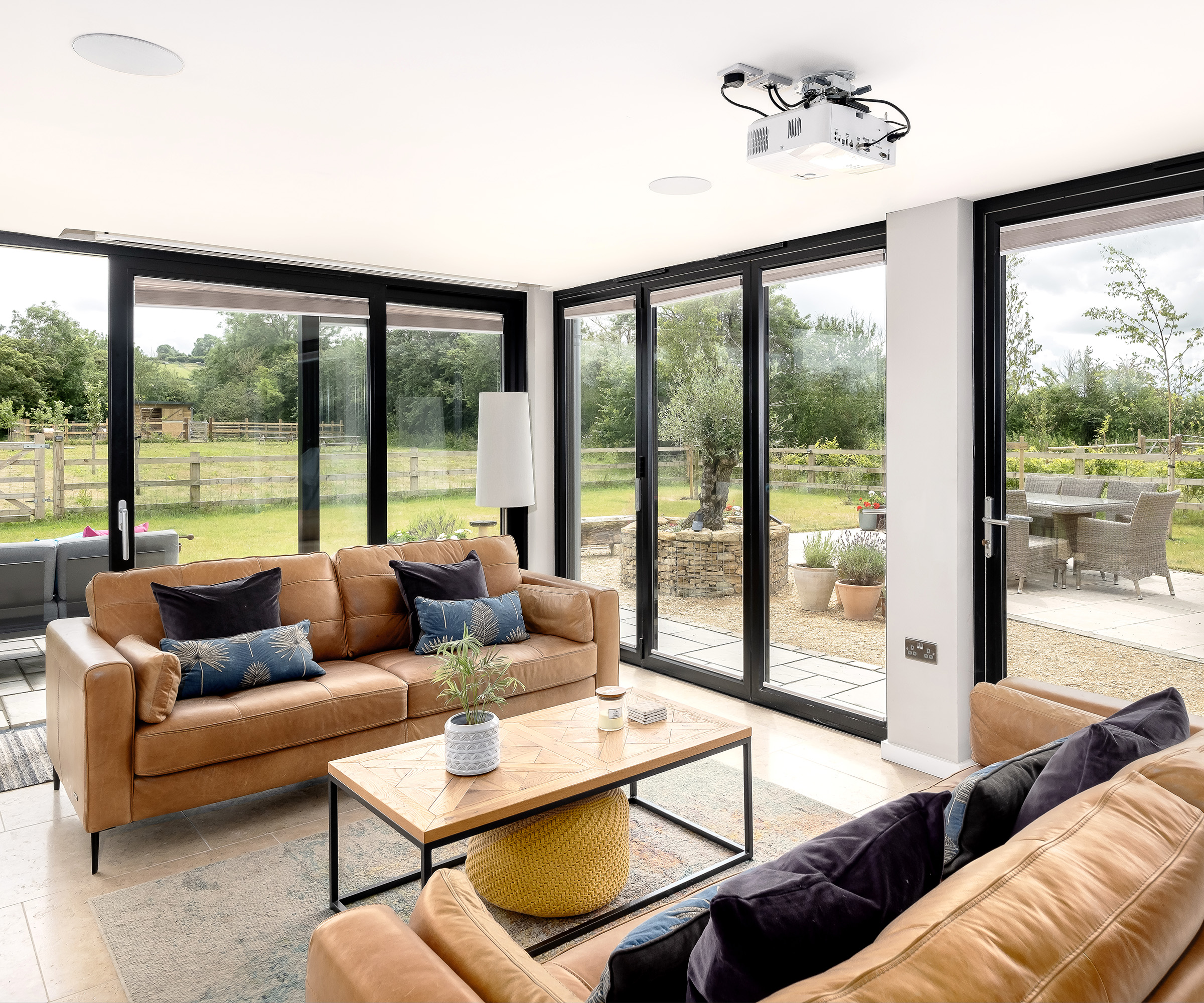 a seating area with two tan leather sofas opposite each other with coffee table in between with glass sliding doors and floor to ceiling glazing