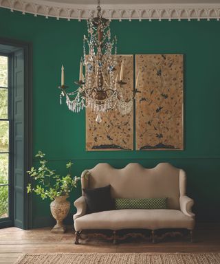 living room with green walls and antique sofa and artwork and chandelier