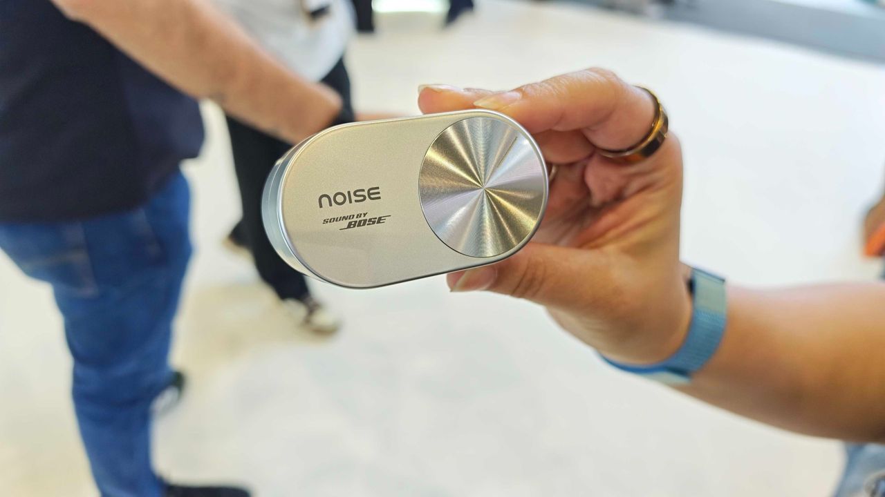 Noise Master Buds Open, held in a hand in a big expo center