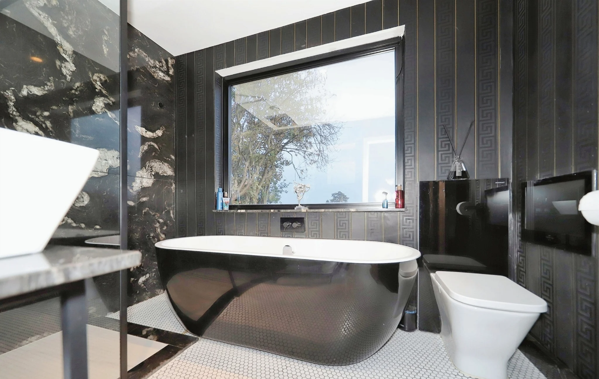 A black and white bathroom with a black bath in the centre of the room
