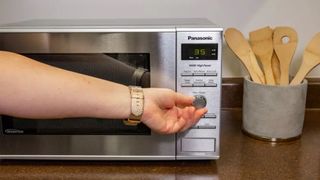 a hand using the dial on the Panasonic NN-SD372SR microwave