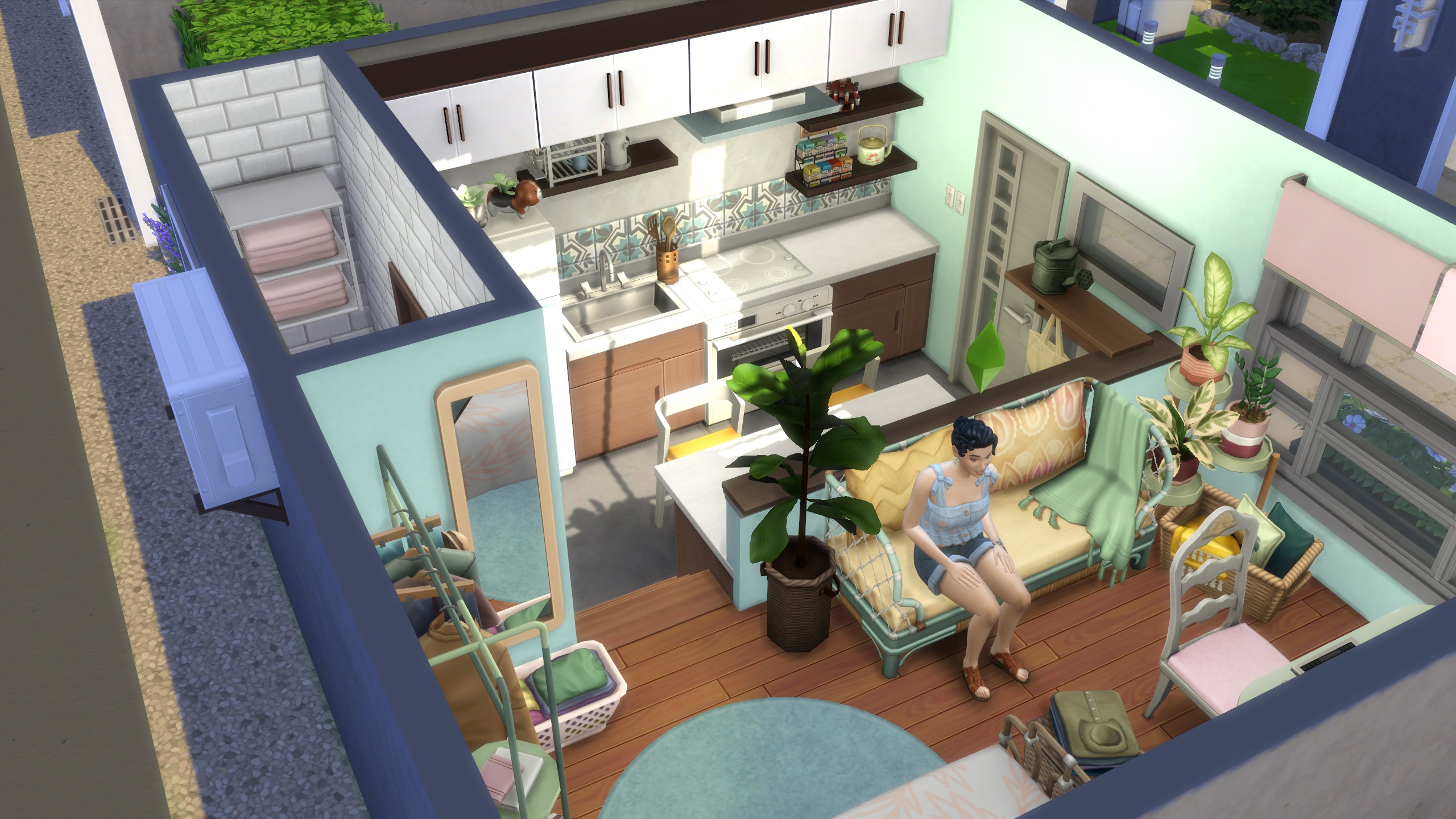 Suggerimenti per la costruzione di The Sims 4 - Un Sim in un loft molto piccolo con un arredamento accogliente e disordinato.