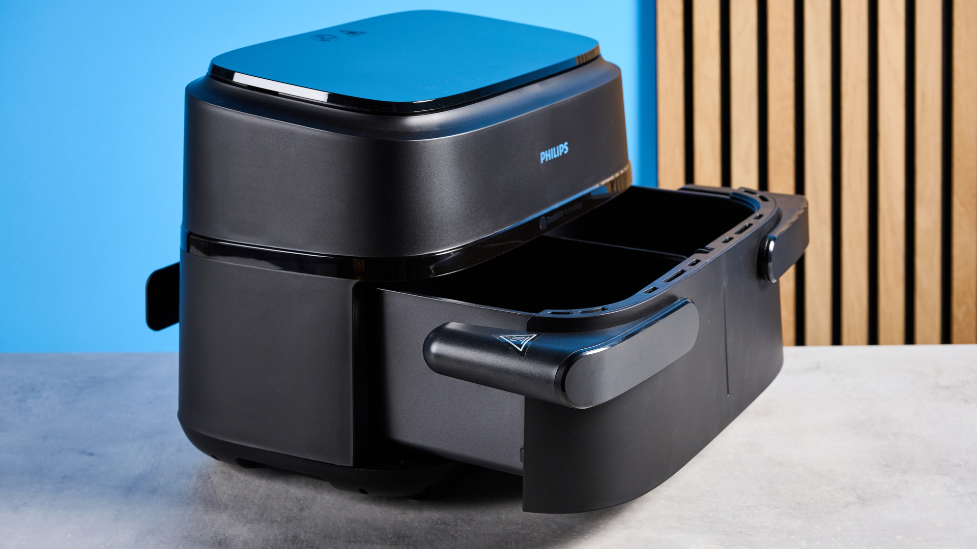 The Philips 1000 Series FlexDrawer Air Fryer photographed in front of a blue background.