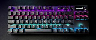 black compact keyboard with multi-color lighting against black background