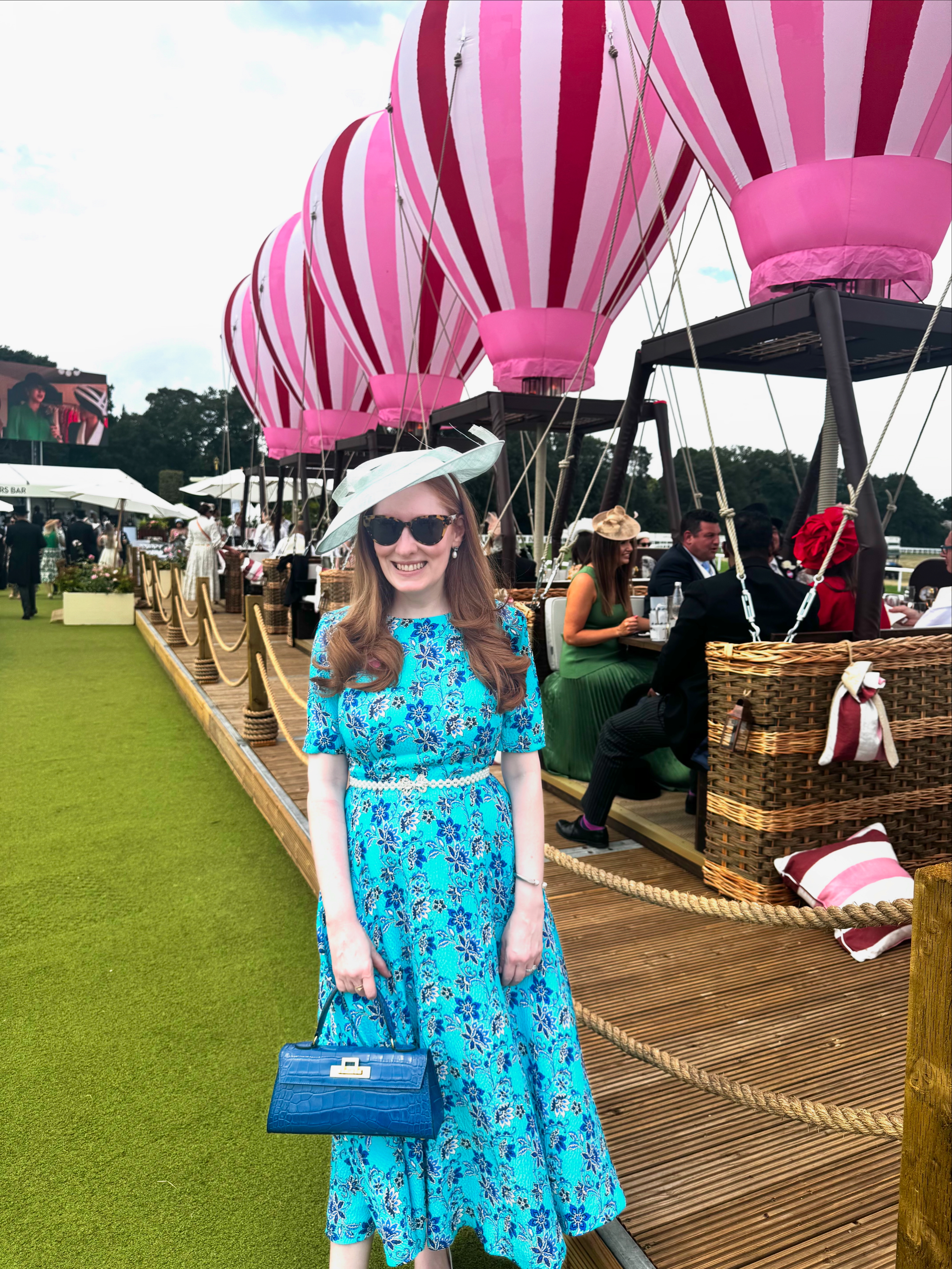 Kristin Contino wearing a blue floral dress in front of hot air balloons