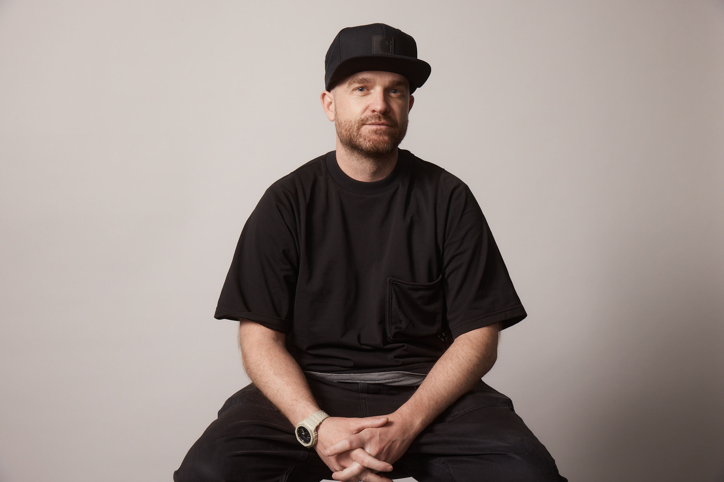 man with a baseball cap on and a dark t-shirt and trousers