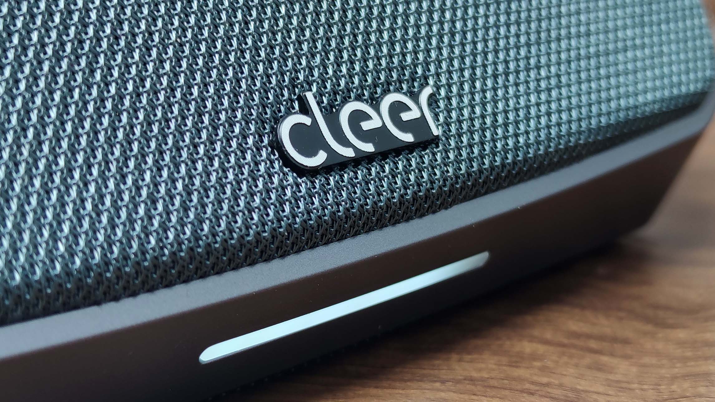 Cleer Audio Scene on wooden table, showing the logo and light on the front
