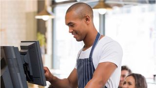 A whitepaper from TouchBistro covering Key considerations to take into account when purchasing a legacy POS system, with image of smiling waiter using a POS