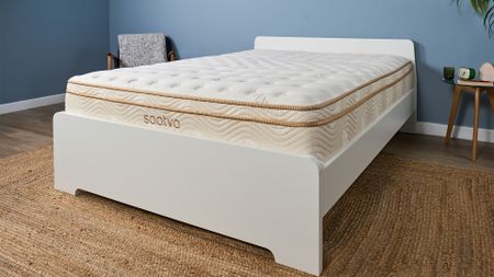The Saatva Classic Mattress on a white bed frame in a blue room